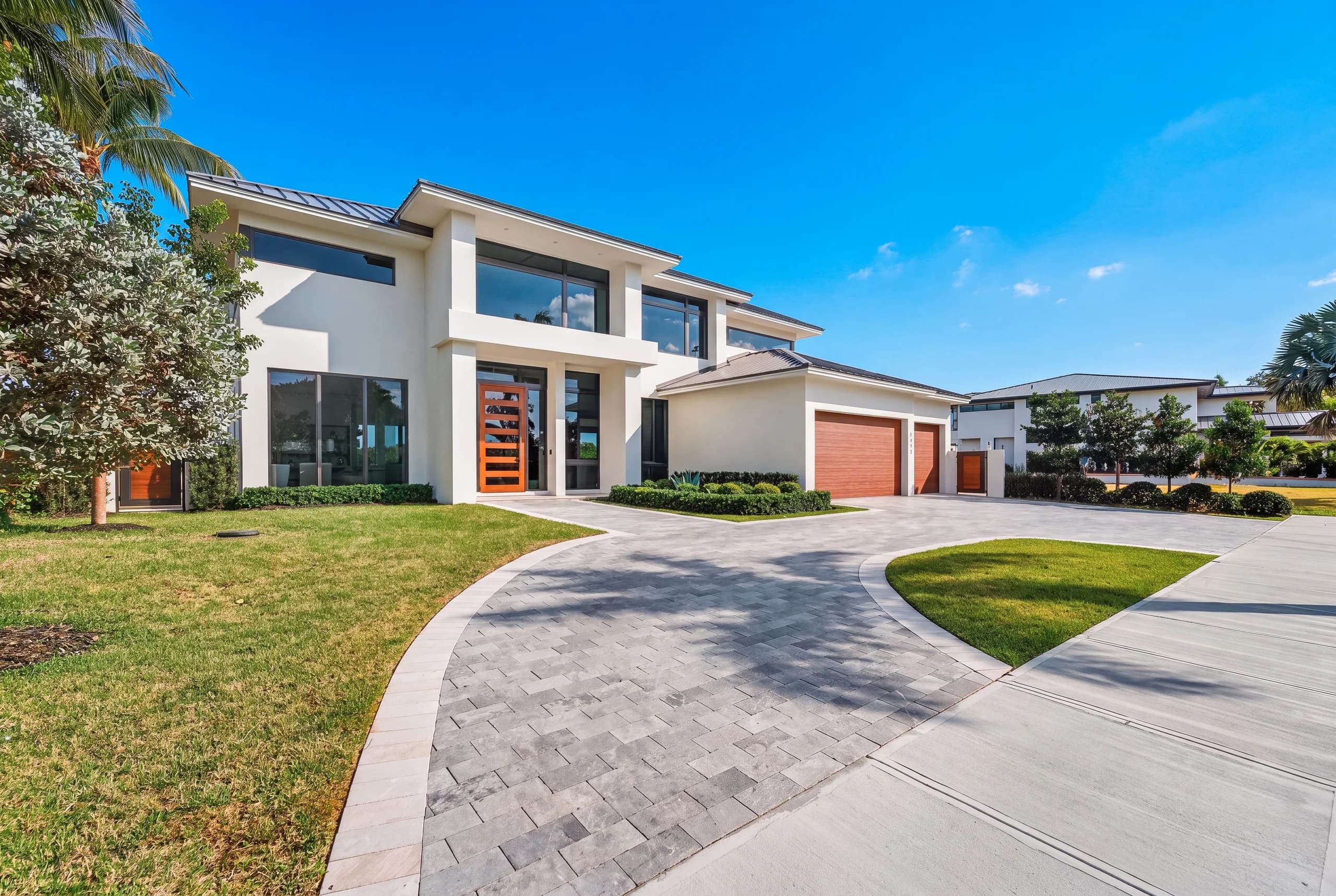 Contemporary waterfront residence with a broad driveway and tropical landscaping