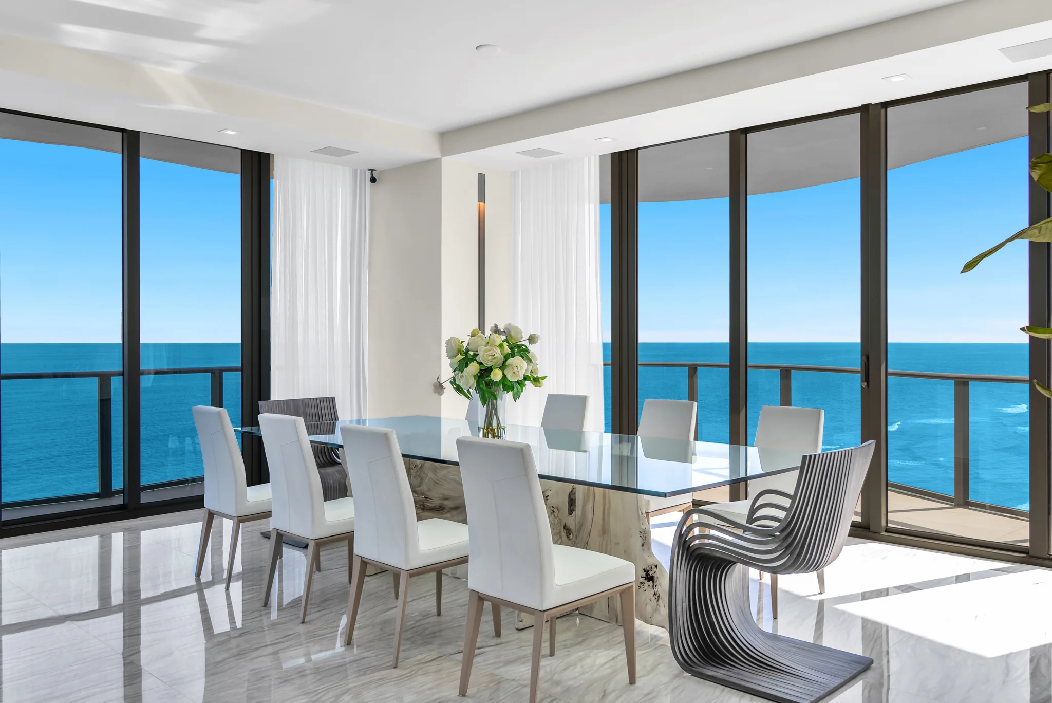 Oceanfront dining room framed by curved glass and Atlantic views