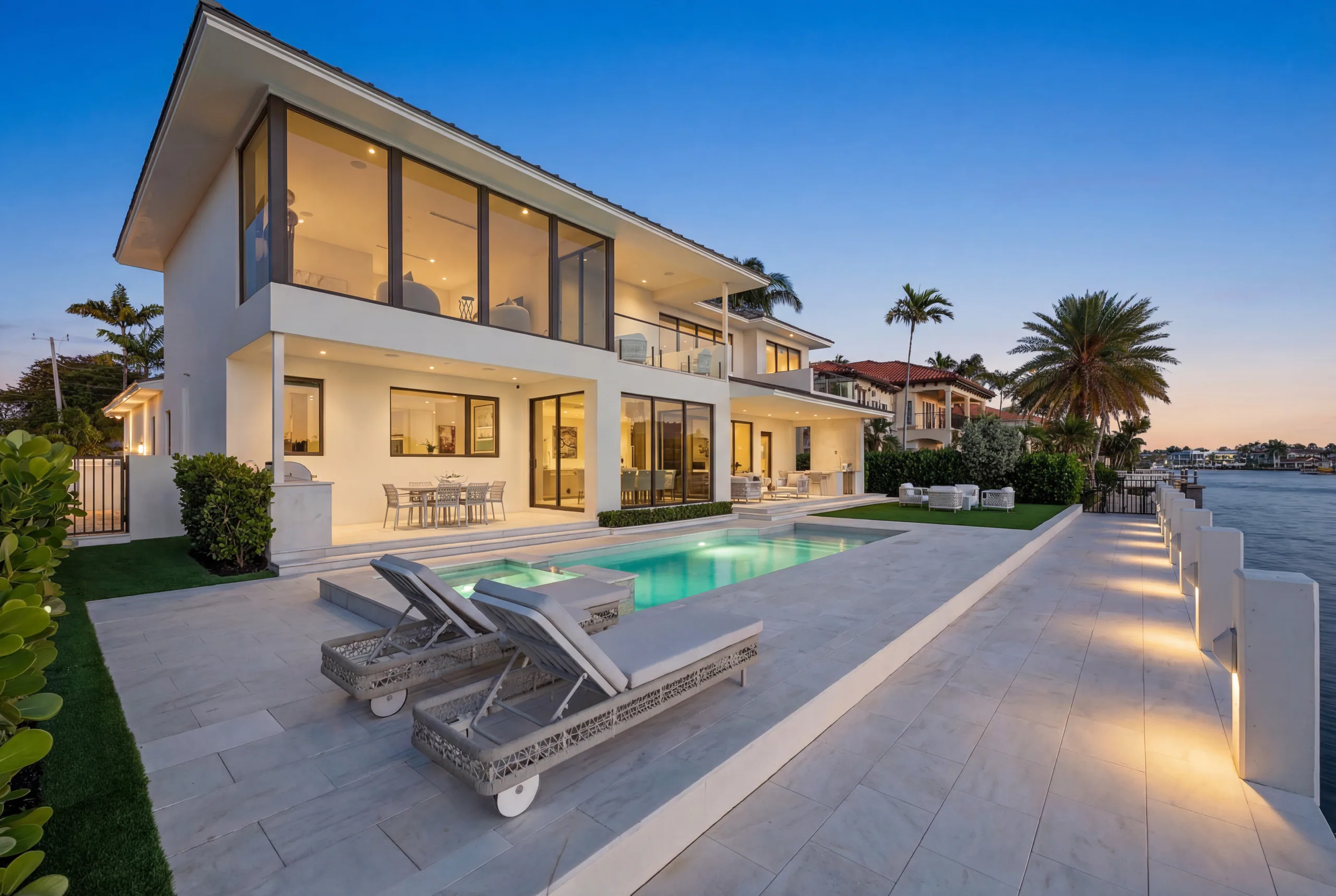 Waterfront residence, pool, and illuminated seawall at blue hour