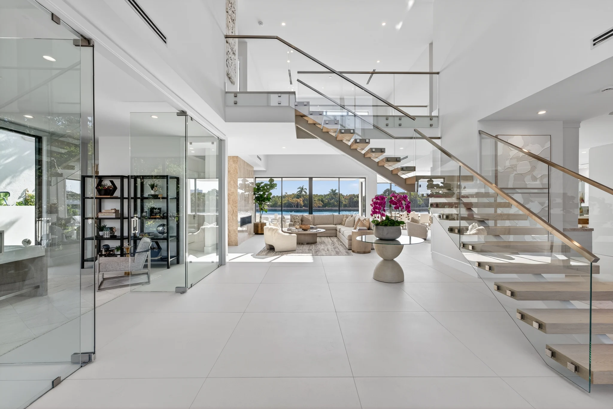 Bright double-height entrance with a floating wood staircase and water views