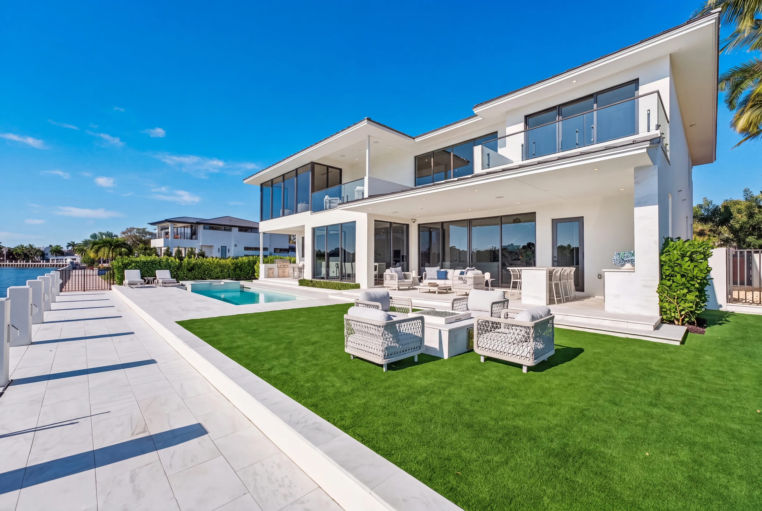 Sunny waterfront residence with a swimming pool, lawn, and outdoor seating